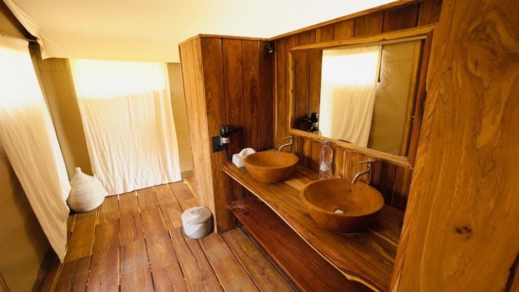 Salle de bain d'une tente de safari : vasques en bois et plancher en bois