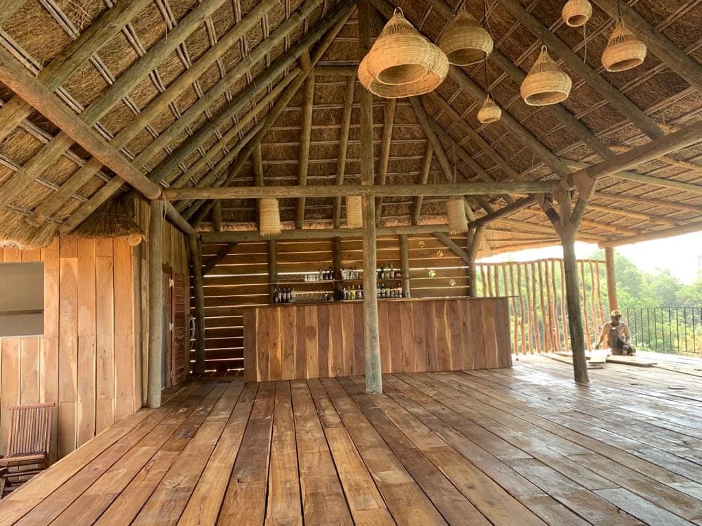 Espace lounge sous une grande charpente en bois et toit de paille, plancher en bois