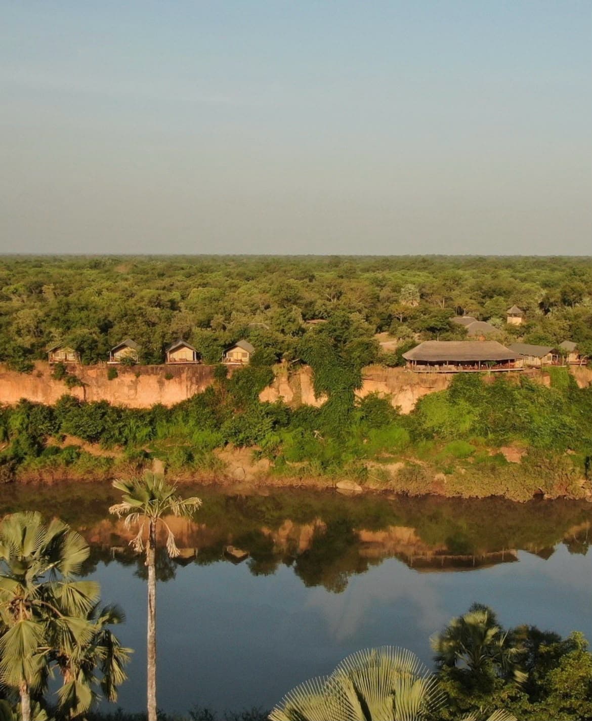 Niokolodge sur la falaise au-dessus du fleuve, vu depuis la rive opposée