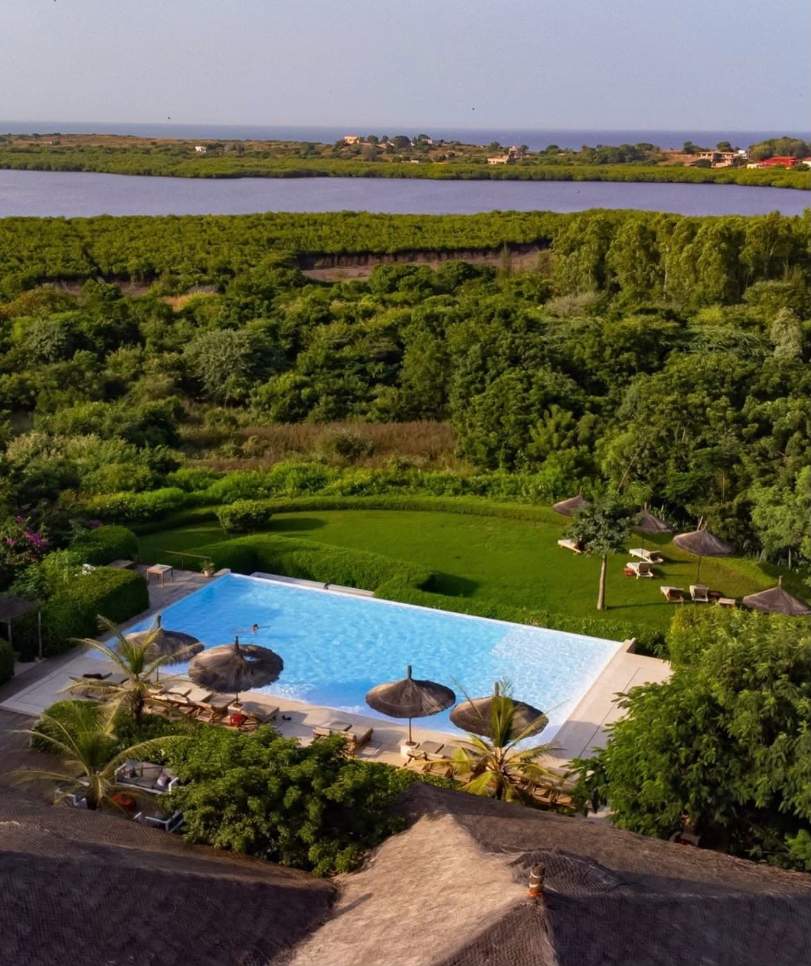 Vue aérienne des Manguiers de Guéréo : la piscine à débordement, les jardins et la lagune de la Somone au loin